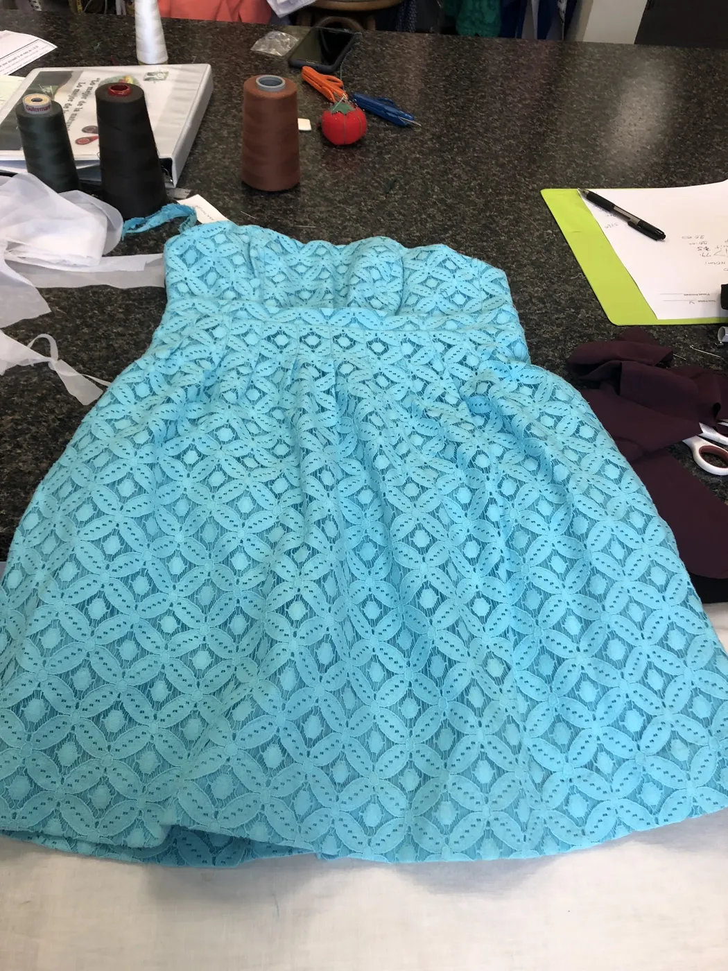 A blue lace dress laid out on the cutting table, ready for alterations