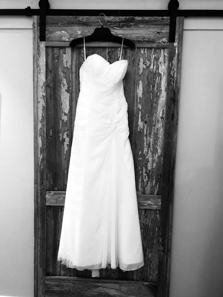 A strapless wedding gown hanging on a rustic wooden door